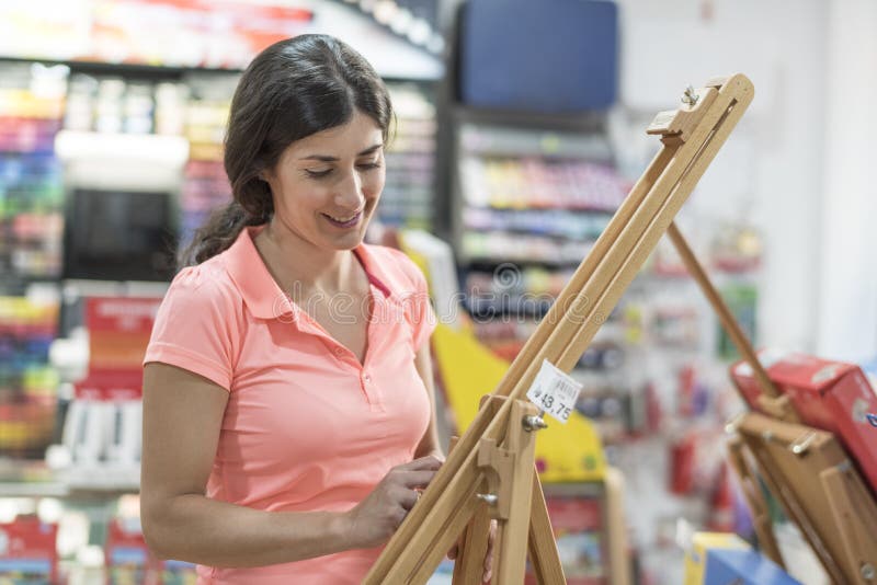 Mujer que mira en tienda una sonrisa del caballete fotos de archivo Mujer que mira en tienda una sonrisa del caballete fotos de archivo