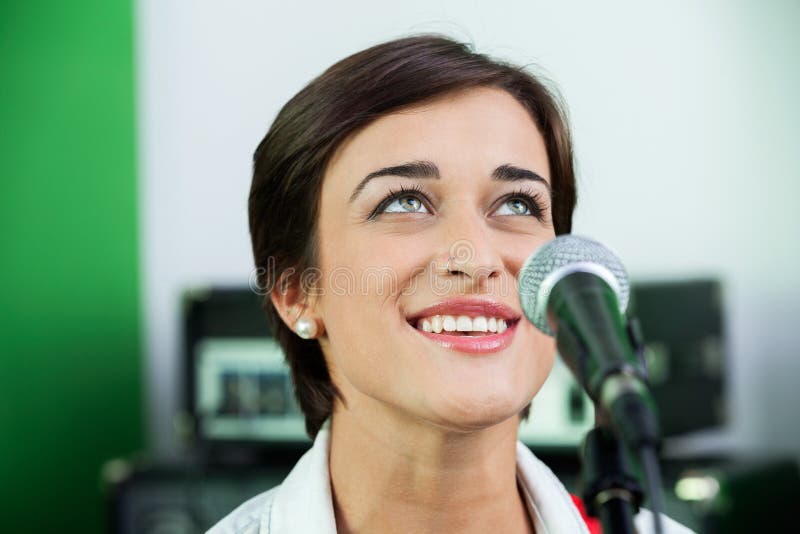 Mujer que mira para arriba mientras que canta en el estudio de grabación imagen de archivo libre de regalías Mujer que mira para arriba mientras que canta en el estudio de grabación imagen de archivo libre de regalías