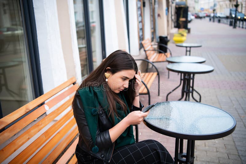 Mujer que mira smartphone el trastorno de la sensación del café de la calle imagen de archivo libre de regalías Mujer que mira smartphone el trastorno de la sensación del café de la calle imagen de archivo libre de regalías