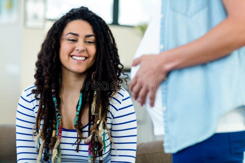 Mujer que mira su vientre embarazada de los socios imagenes de archivo Mujer que mira su vientre embarazada de los socios imagenes de archivo