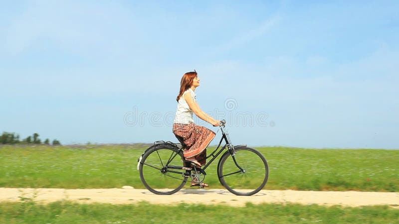 Mujer que monta una bici del vintage en una mañana de la primavera almacen de metraje de vídeo