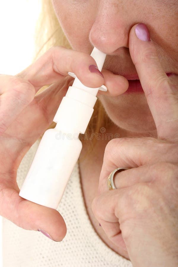 Close-up of woman spraying nasal spray in nostril and holding other nostril for effectiveness. Close-up of woman spraying nasal spray in nostril and holding other nostril for effectiveness.