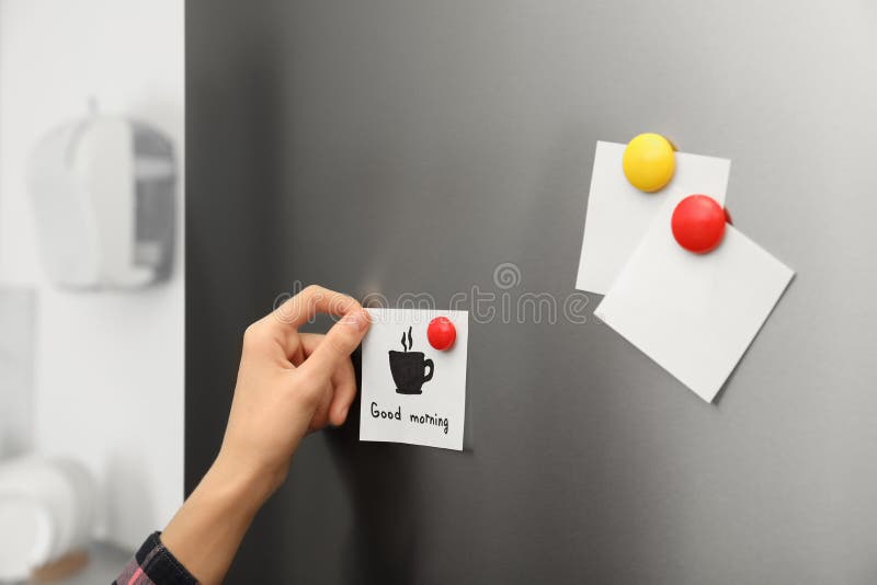 Mujer que pone la hoja de papel en puerta del refrigerador en casa foto de archivo libre de regalías Mujer que pone la hoja de papel en puerta del refrigerador en casa foto de archivo libre de regalías