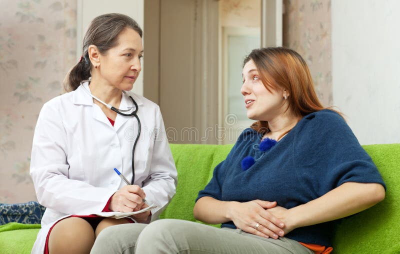 Mujer que se queja al doctor por dolor abdominal imágenes de archivo libres de regalías Mujer que se queja al doctor por dolor abdominal imágenes de archivo libres de regalías
