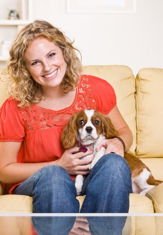 Mujer que se sienta en el sofá con el perro fotografía de archivo libre de regalías Mujer que se sienta en el sofá con el perro fotografía de archivo libre de regalías