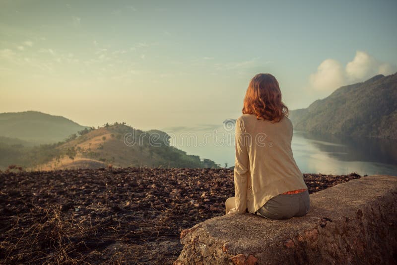 Mujer que se sienta en roca inusual en la salida del sol foto de archivo libre de regalías Mujer que se sienta en roca inusual en la salida del sol foto de archivo libre de regalías