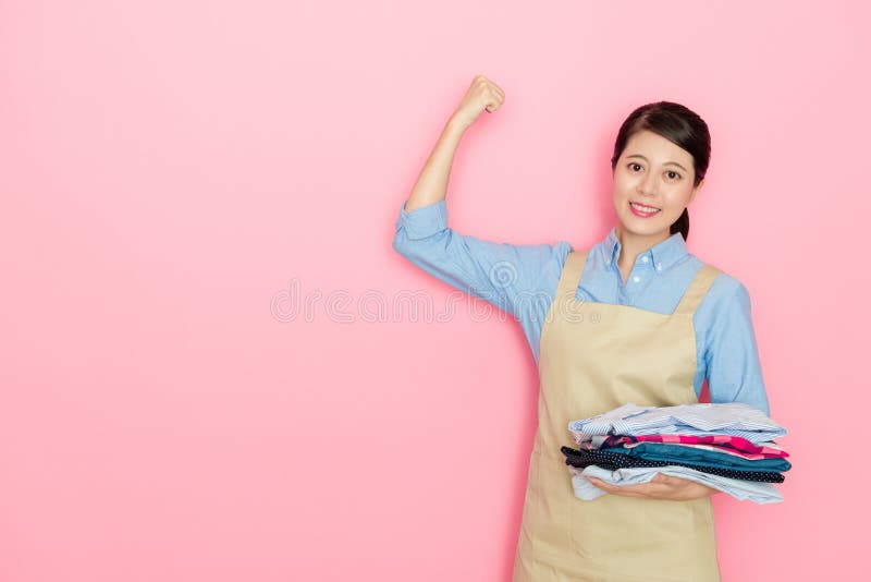 Mujer que sostiene la ropa limpia que muestra el brazo potente foto de archivo libre de regalías Mujer que sostiene la ropa limpia que muestra el brazo potente foto de archivo libre de regalías