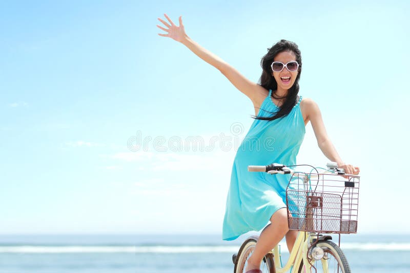 Mujer que tiene bicicleta del montar a caballo de la diversión en la playa