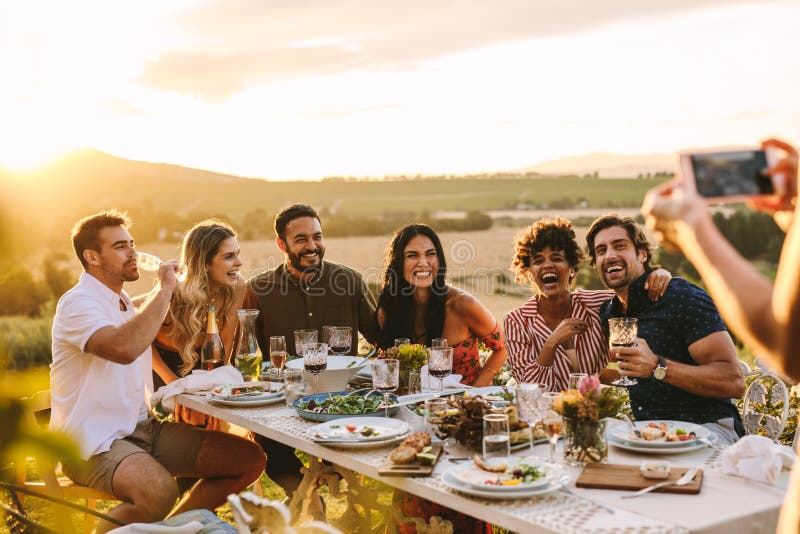 Mujer que toma la imagen de sus amigos en el partido de cena imágenes de archivo libres de regalías Mujer que toma la imagen de sus amigos en el partido de cena imágenes de archivo libres de regalías