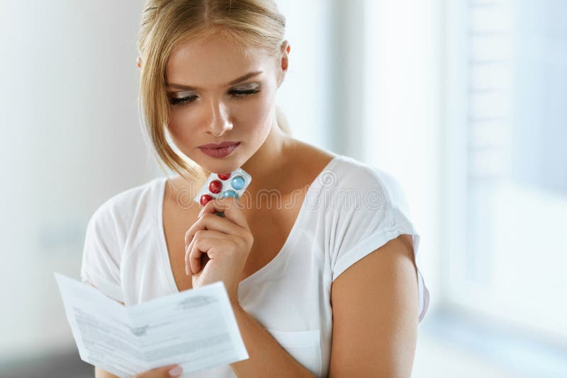 Mujer que toma la medicina Hembra con las píldoras que lee instrucciones
