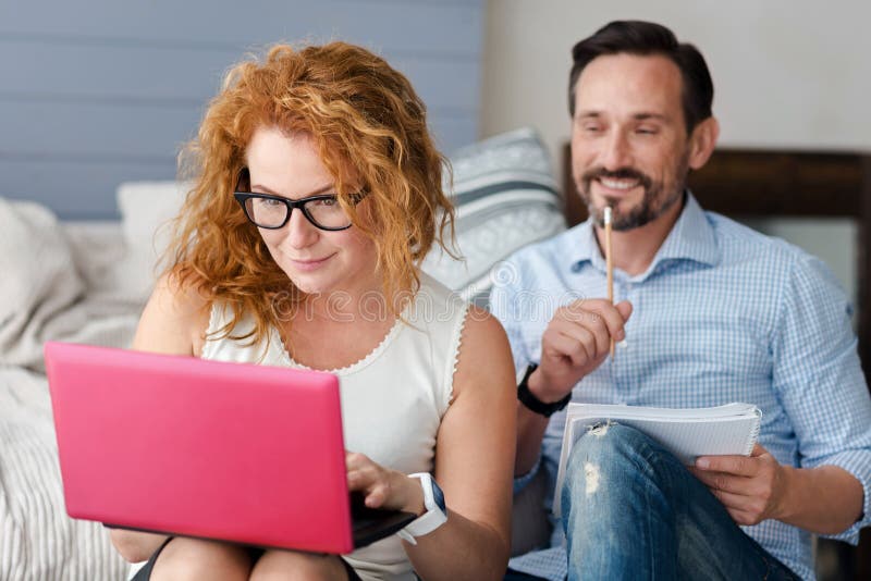 Mujer que trabaja con el ordenador portátil mientras que hombre que toma notas foto de archivo Mujer que trabaja con el ordenador portátil mientras que hombre que toma notas foto de archivo