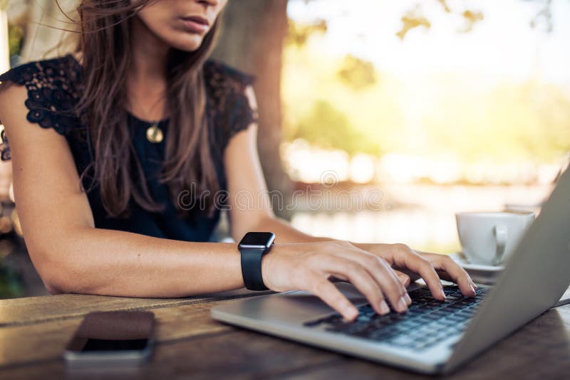 Mujer que trabaja en el ordenador portátil en un café al aire libre imagenes de archivo Mujer que trabaja en el ordenador portátil en un café al aire libre imagenes de archivo