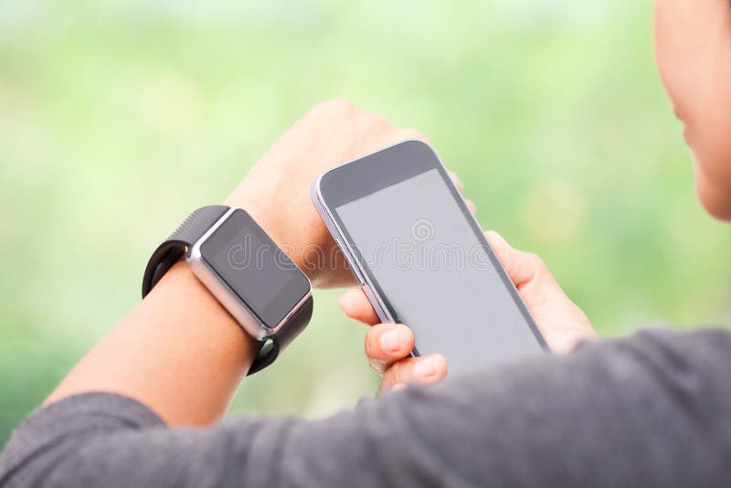 Mujer que usa el reloj elegante y el teléfono elegante fotos de archivo libres de regalías Mujer que usa el reloj elegante y el teléfono elegante fotos de archivo libres de regalías