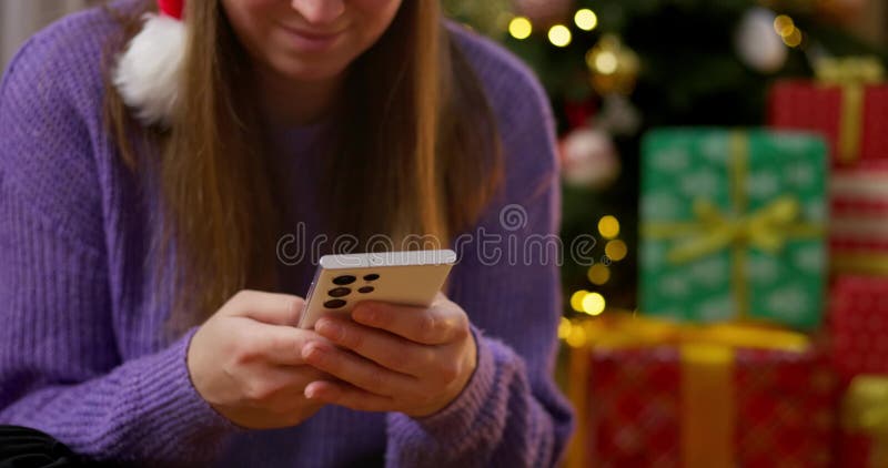 Mujer que usa smartphone cerca del árbol de navidad almacen de video