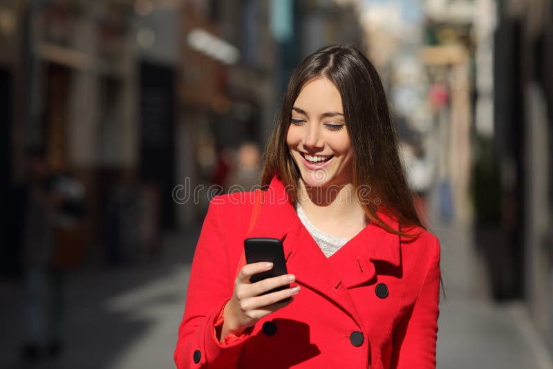 Mujer que usa un teléfono elegante mientras que paseo en la calle fotos de archivo Mujer que usa un teléfono elegante mientras que paseo en la calle fotos de archivo