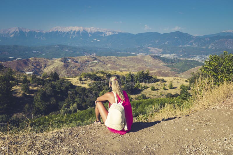 Mujer que viaja que se sienta cerca de la montaña y que mira lejos imagen de archivo libre de regalías Mujer que viaja que se sienta cerca de la montaña y que mira lejos imagen de archivo libre de regalías