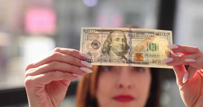 Mujer revisa billetes de cien dólares para detectar falsificaciones