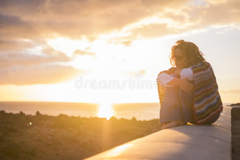 Mujer rizada hermosa que se sienta en una pared y disfrutar de la sensaci?n del tiempo de la puesta del sol la sensaci?n de la li foto de archivo libre de regalías Mujer rizada hermosa que se sienta en una pared y disfrutar de la sensaci?n del tiempo de la puesta del sol la sensaci?n de la li foto de archivo libre de regalías