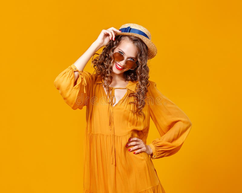 Mujer rizada joven hermosa en sombrero y gafas de sol del verano en fondo amarillo fotos de archivo libres de regalías