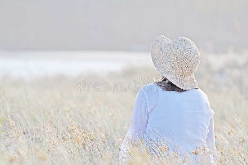 Mujer romántica que se sienta en hierba larga alta