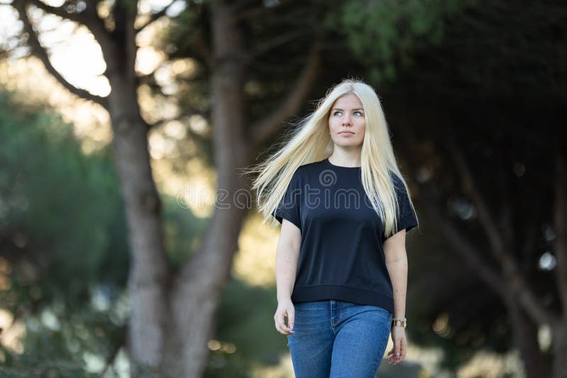 Mujer rubia caminando por una calle urbana imagen de archivo