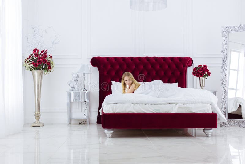 Mujer rubia chic en blanco de lujo con dormitorio rojo. interior rico y caro