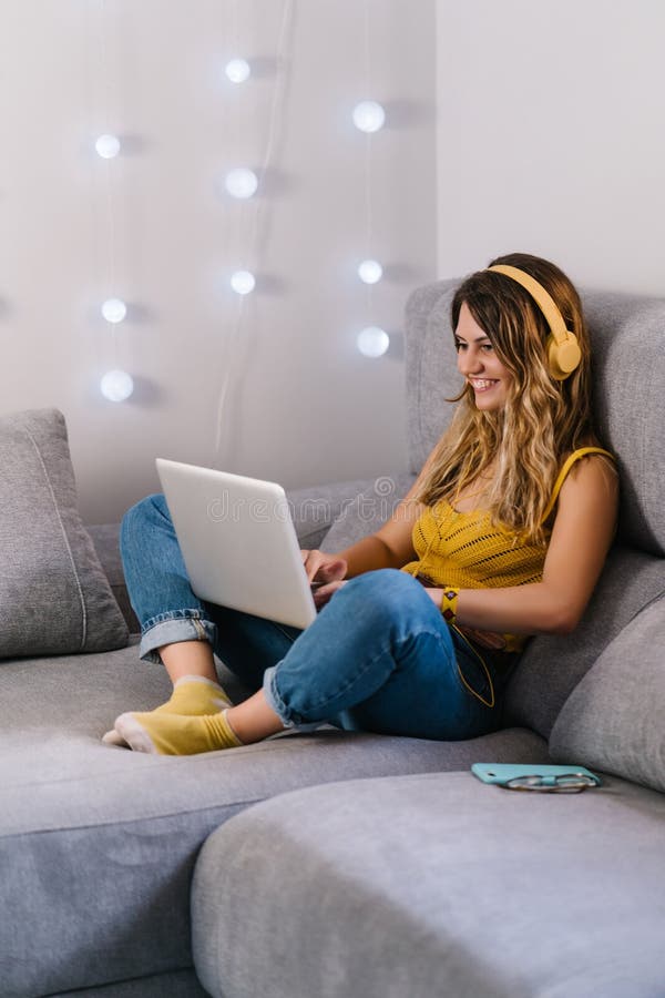 Mujer rubia con la cabeza amarilla y el auricular usando la laptop en casa foto de archivo libre de regalías