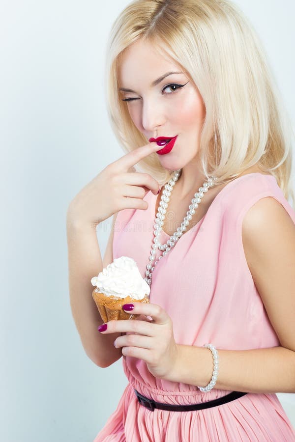 Mujer rubia elegante atractiva hermosa con maquillaje brillante en vestido rosado en el estudio en un fondo blanco que se sienta imágenes de archivo libres de regalías Mujer rubia elegante atractiva hermosa con maquillaje brillante en vestido rosado en el estudio en un fondo blanco que se sienta imágenes de archivo libres de regalías