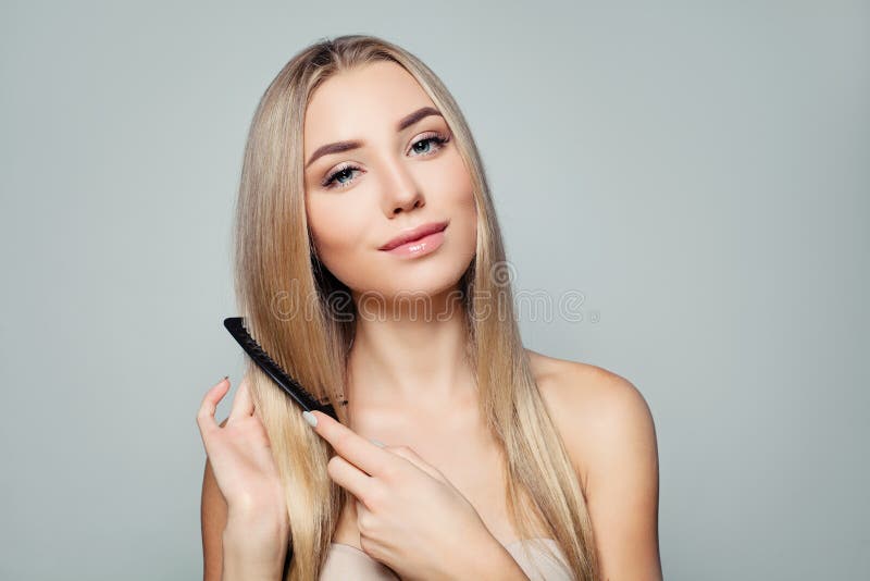 Beautiful blonde woman with long healthy straight hair combing hair. Haircare concept. Girl combs hair. Beautiful blonde woman with long healthy straight hair combing hair. Haircare concept. Girl combs hair.