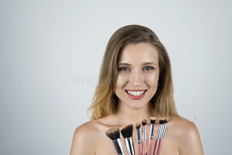 Mujer rubia hermosa joven que lleva a cabo el fondo blanco aislado cepillos rosados imagenes de archivo Mujer rubia hermosa joven que lleva a cabo el fondo blanco aislado cepillos rosados imagenes de archivo