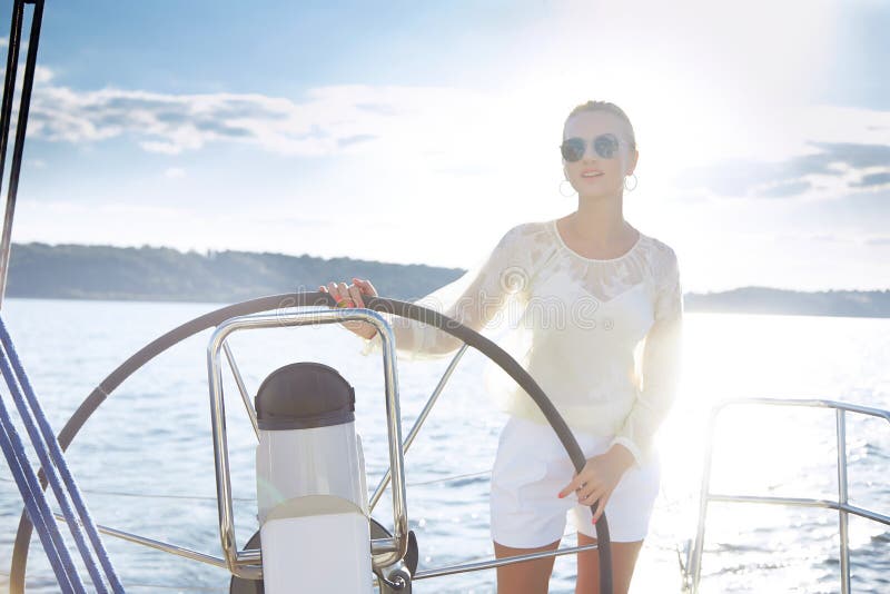 Mujer rubia joven atractiva hermosa, montando un barco en el agua, itinerario, maquillaje hermoso, ropa, verano, sol, cuerpo perf foto de archivo libre de regalías Mujer rubia joven atractiva hermosa, montando un barco en el agua, itinerario, maquillaje hermoso, ropa, verano, sol, cuerpo perf foto de archivo libre de regalías