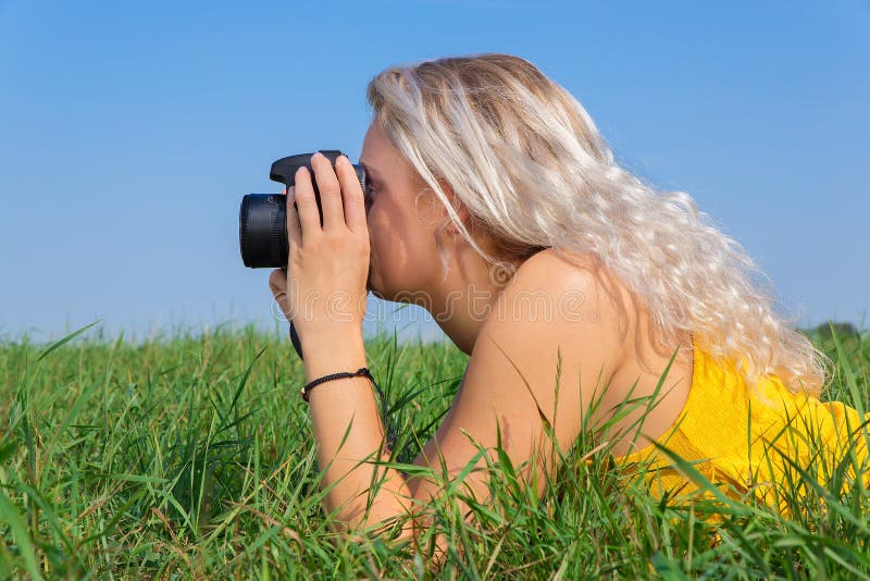 Mujer rubia joven que fotografía en hierba foto de archivo libre de regalías Mujer rubia joven que fotografía en hierba foto de archivo libre de regalías
