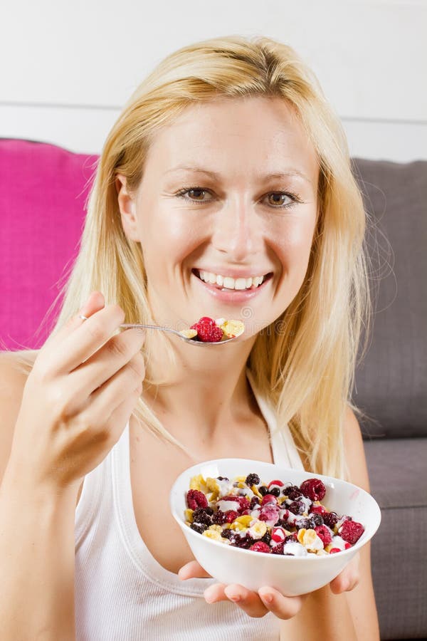 Mujer rubia preciosa que come los cereales con la fruta en el desayuno imagenes de archivo Mujer rubia preciosa que come los cereales con la fruta en el desayuno imagenes de archivo