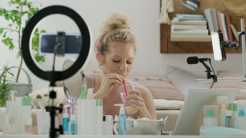 Mujer rubia sonriente influenciante blogger grabando un video tutorial en cámara de smartphone toma un descanso y chats en línea. almacen de metraje de vídeo