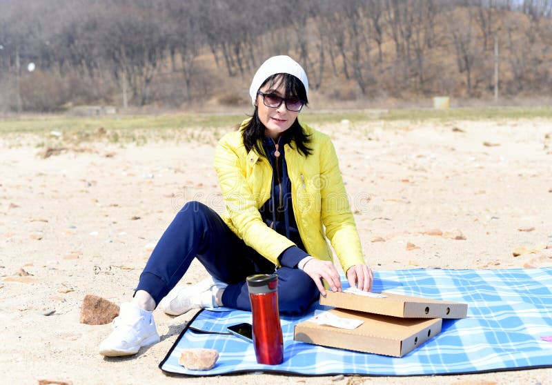 Mujer rusa de 45 años que va a comer pizza mientras está sentada en la playa imágenes de archivo libres de regalías