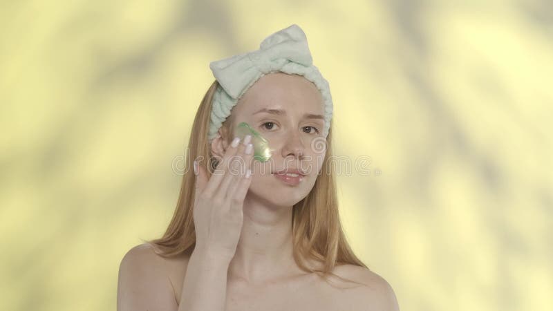 Mujer seminuda con banda de cabello para procedimientos cosméticos en estudio sobre fondo amarillo con resaltado. una mujer almacen de metraje de vídeo