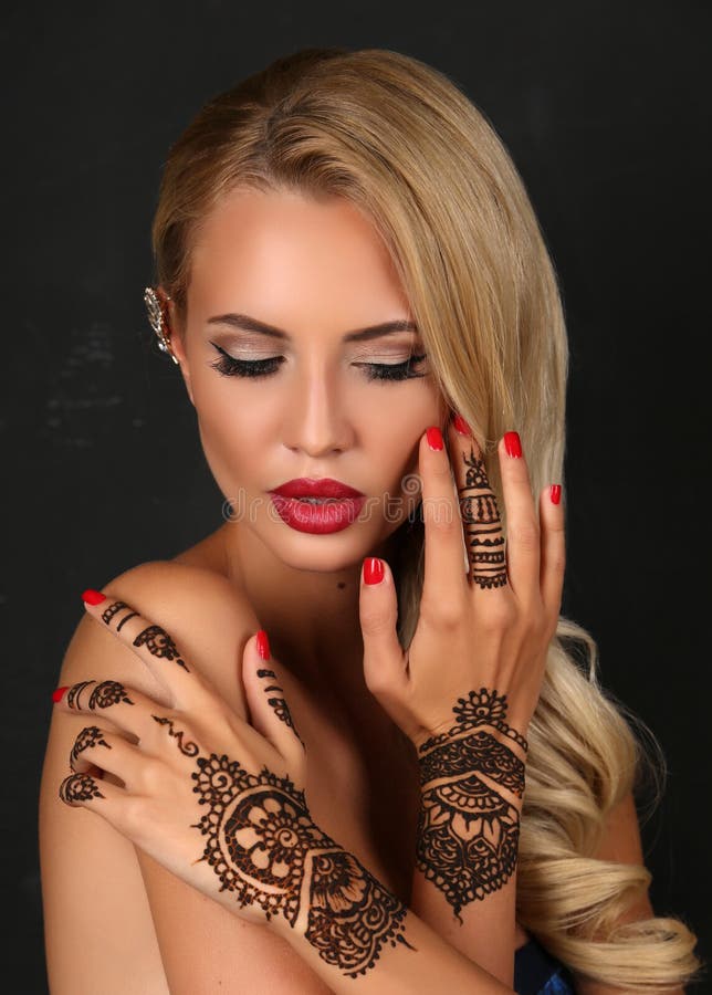 Fashion studio portrait of beautiful sensual woman with blond hair with henna tattoo on hands. Fashion studio portrait of beautiful sensual woman with blond hair with henna tattoo on hands