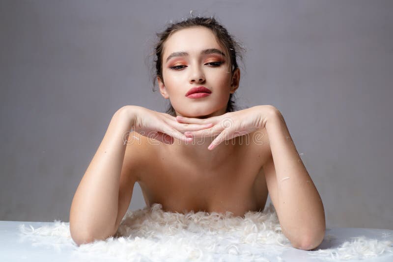 Mujer sensual en las plumas mullidas blancas Buenos d? as Sue? os dulces Piel suave Concepto de Skincare Foco de los cosm? ticos y d fotos de archivo
