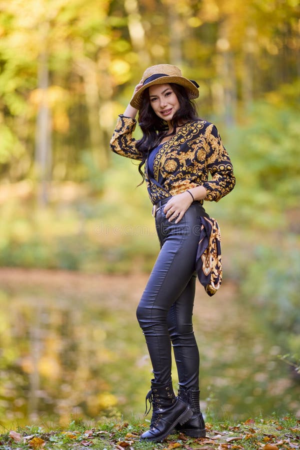 Mujer sentada en un tronco cerca de un lago durante el otoño fotografía de archivo