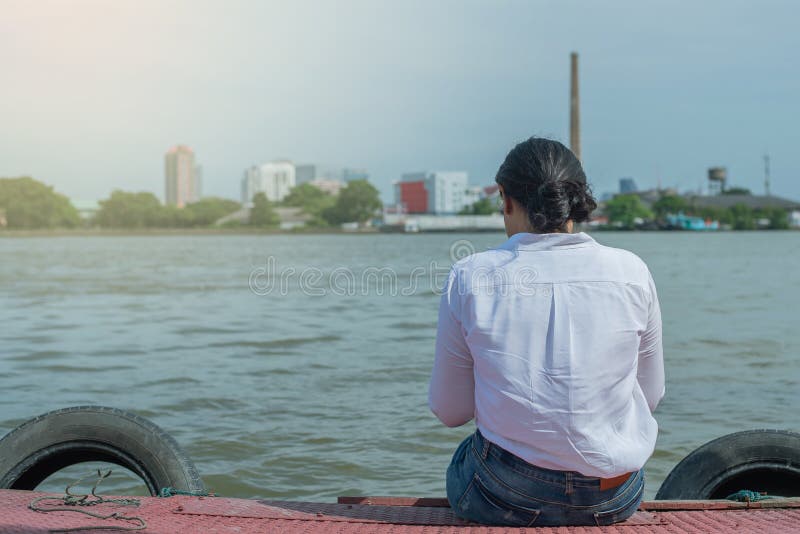 Mujer sentada sola en el puerto mirando al río fotos de archivo Mujer sentada sola en el puerto mirando al río fotos de archivo