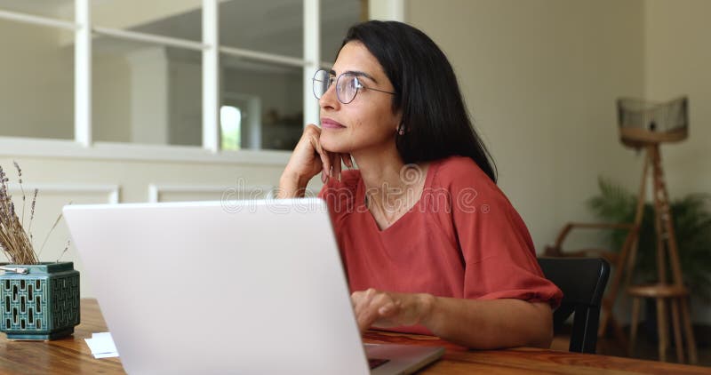 Mujer seria y reflexiva de negocios independiente en gafas que trabajan en laptop almacen de video