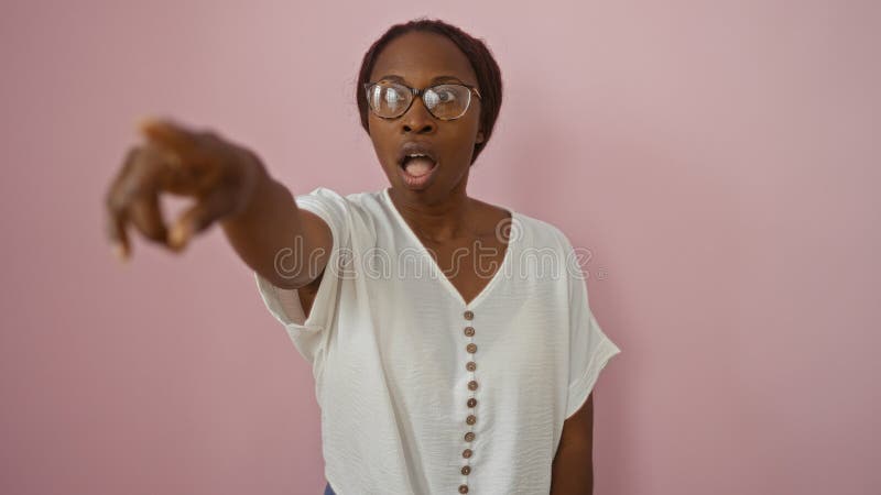 Mujer señalando mientras miraba sorprendida por un entorno rosa aislado imagen de archivo