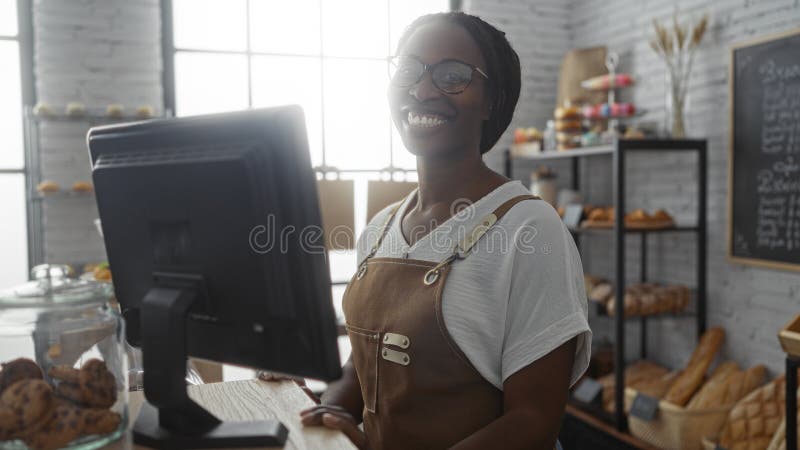 Mujer sonriendo en casa en una panadería con productos horneados en exhibición y trabajando en el mostrador imagenes de archivo