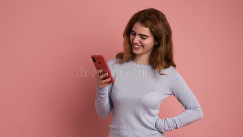Mujer sonriendo a la cámara mientras usa el teléfono móvil almacen de video