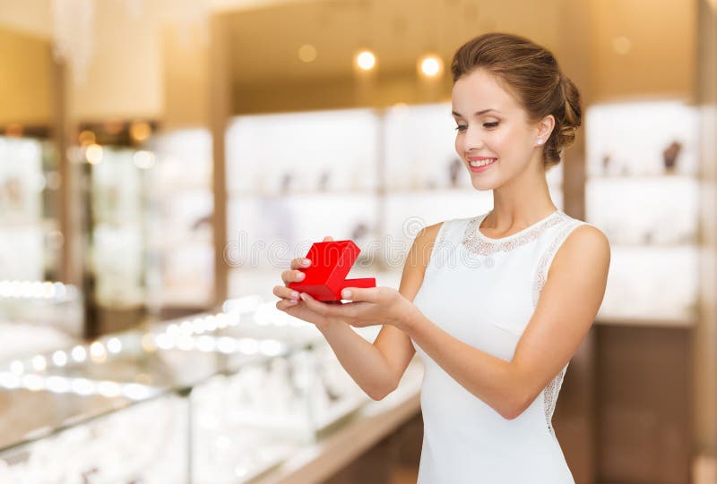 Mujer sonriente con caja de regalo roja en joyería foto de archivo libre de regalías