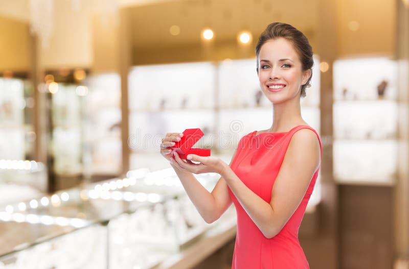 Mujer sonriente con caja de regalo roja en joyería imagenes de archivo
