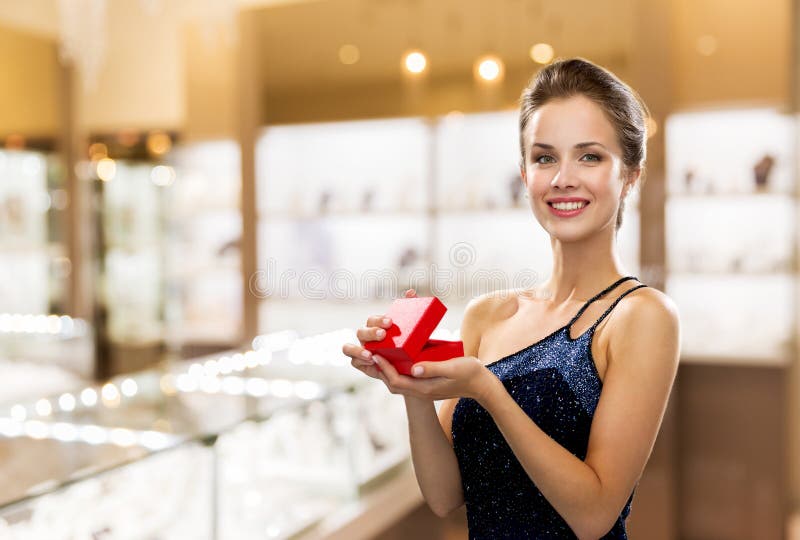 Mujer sonriente con caja de regalo roja en joyería fotos de archivo