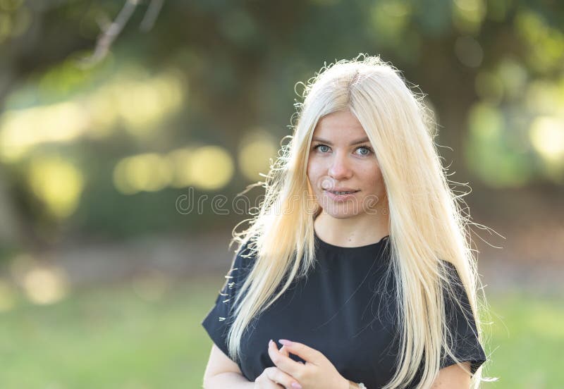 Mujer sonriente con cordones con el pelo rubio en el parque imagen de archivo libre de regalías