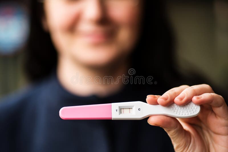 Smiling woman with home pregnancy test showing positive result. Smiling woman with home pregnancy test showing positive result