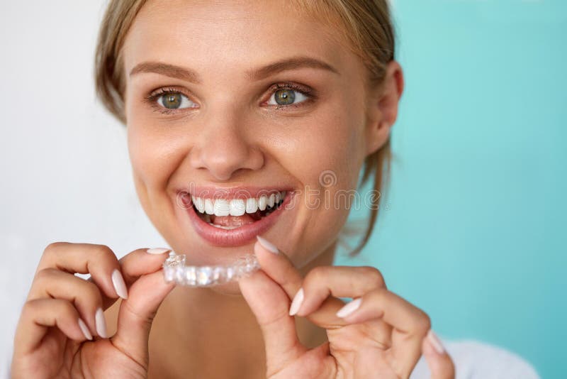 Mujer sonriente con sonrisa hermosa usando los dientes que blanquea la bandeja